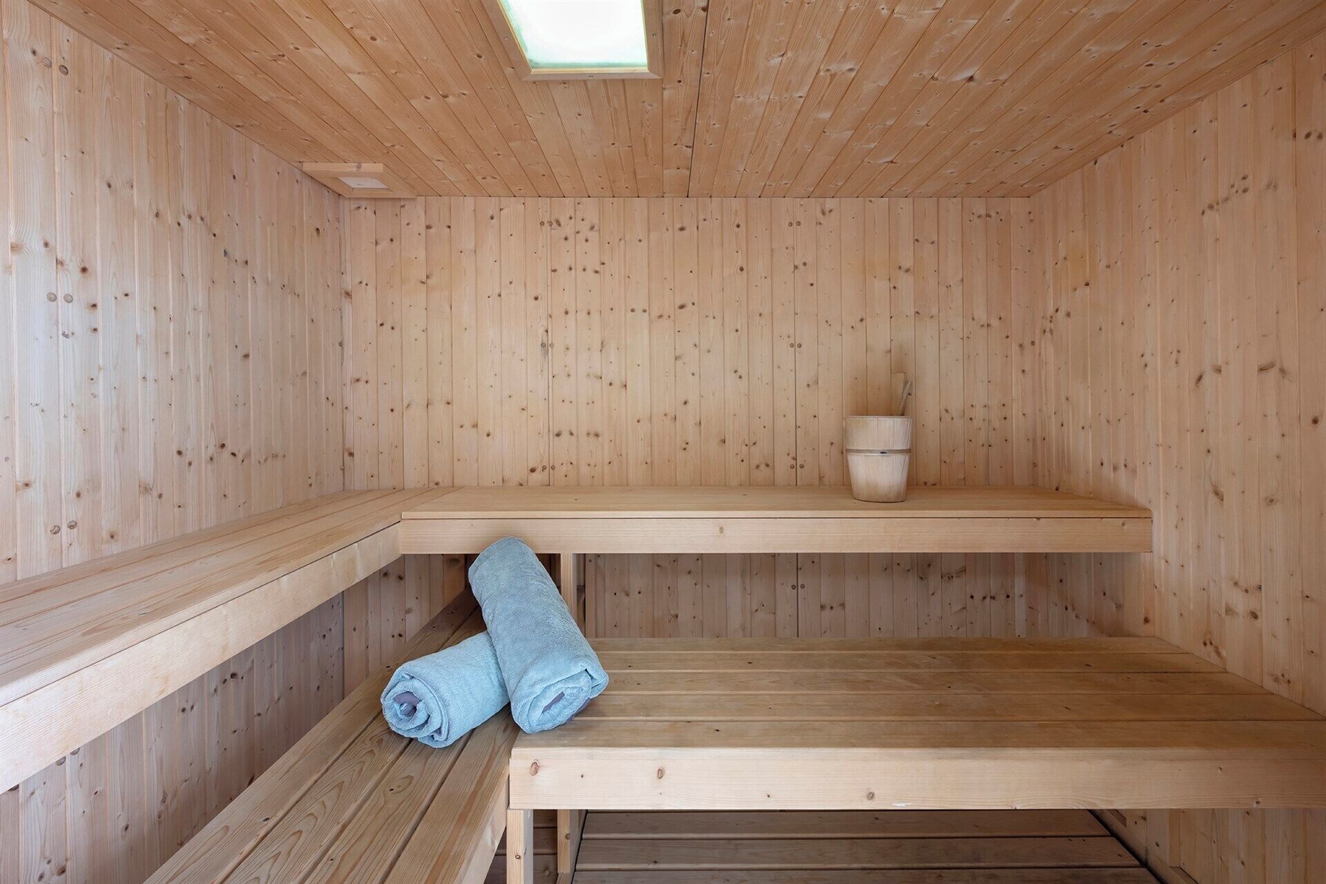 Un espai de sauna de fusta amb bancs i una petita prestatgeria.