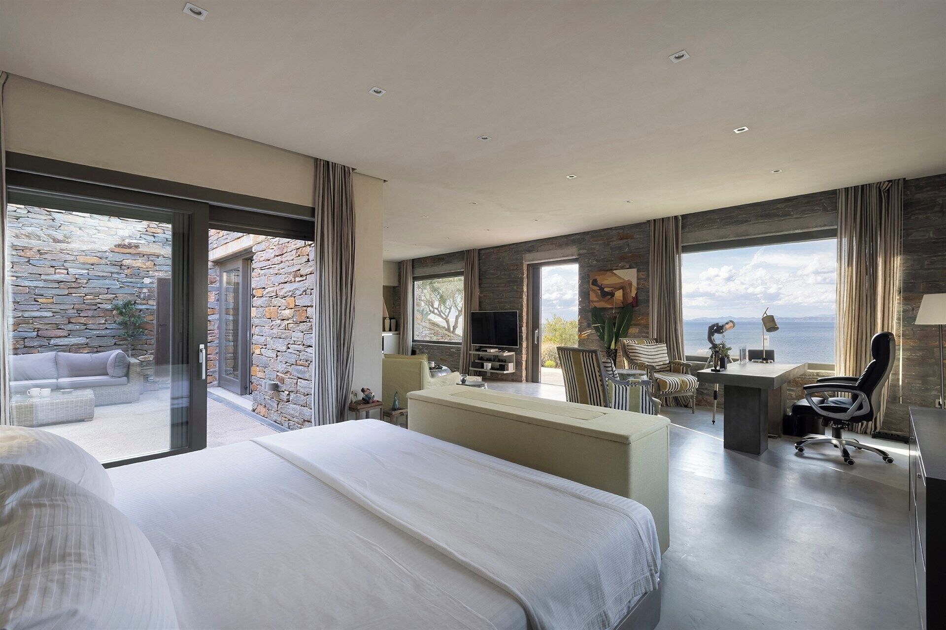 Un dormitorio moderno con una cama grande, un escritorio y vista al mar.