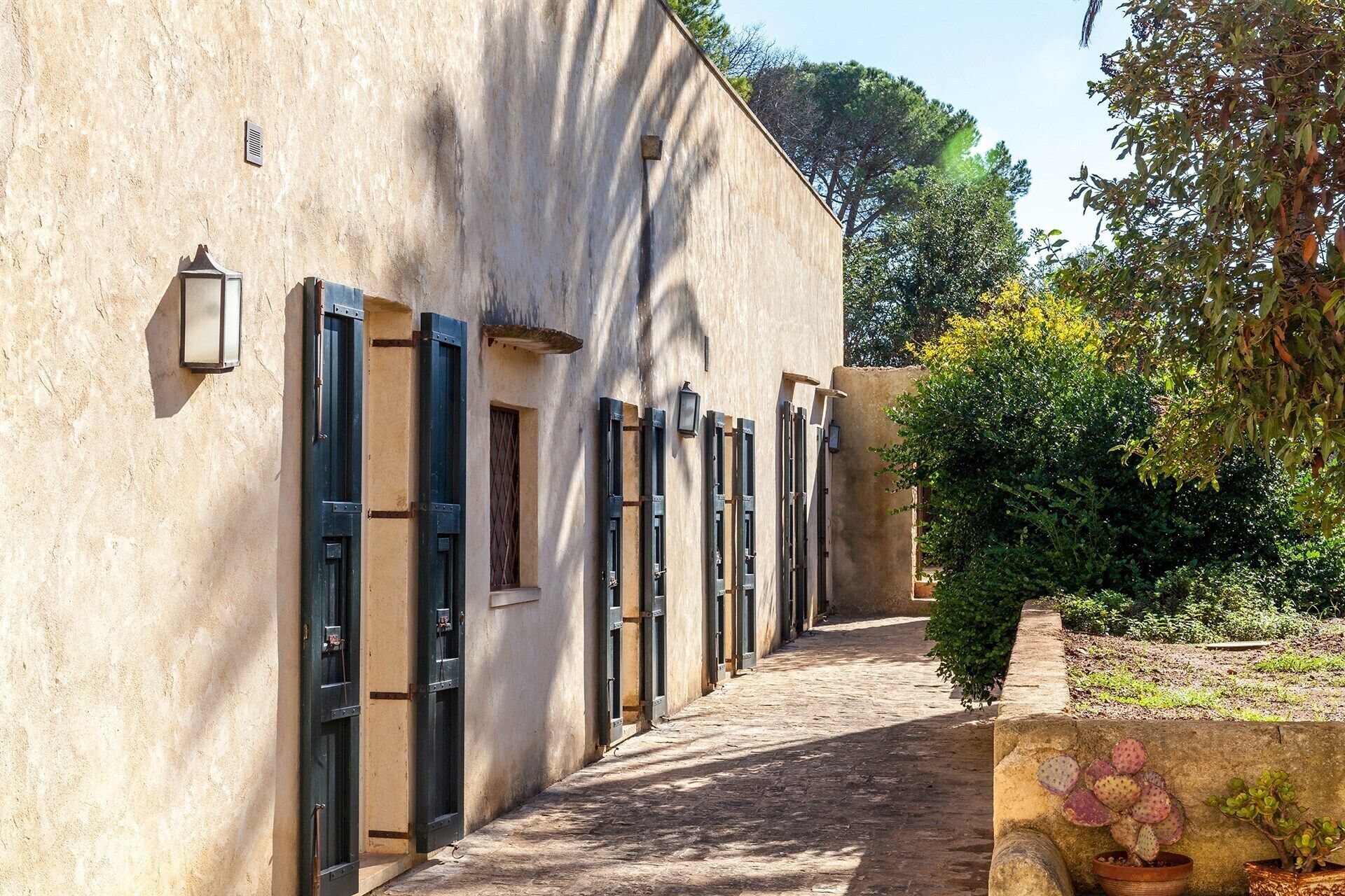 A narrow alleyway with a row of doors and windows, leading to a building with a textured facade.
