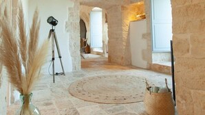 A stone-walled room with a high ceiling, a tripod, and a vase with pampas grass.