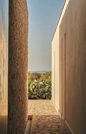 Un étroit sentier menant à un bâtiment d’où l’on a une vue sur la mer.