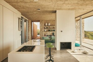 Una cocina moderna con una isla central, una pared de piedra y vistas a través de un ventanal.