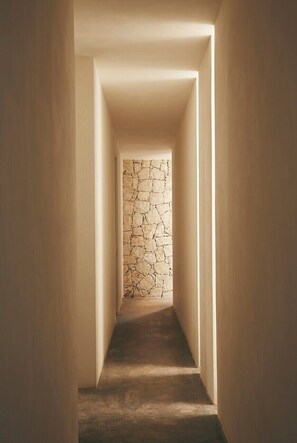 Un couloir étroit, avec un mur à motifs au fond et un sol recouvert de moquette.