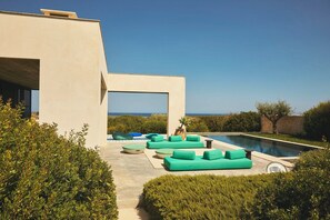 Un espacio al aire libre moderno con sofás verdes y una piscina.