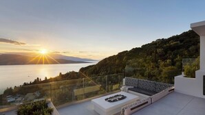 A modern outdoor terrace with a glass balustrade overlooking a lake and mountains during sunset. - Casa Rosemary - Two Bedroom Villa, Sleeps 4 (Lefkada City)