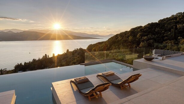 A modern infinity pool with lounge chairs, overlooking a lake and mountains during sunset. - Casa Rosemary - Two Bedroom Villa, Sleeps 4 (Lefkada City)