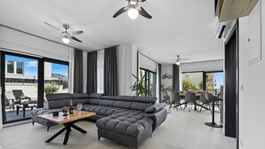 Una sala de estar moderna con un sofá modular, una mesa de centro y ventiladores de techo.