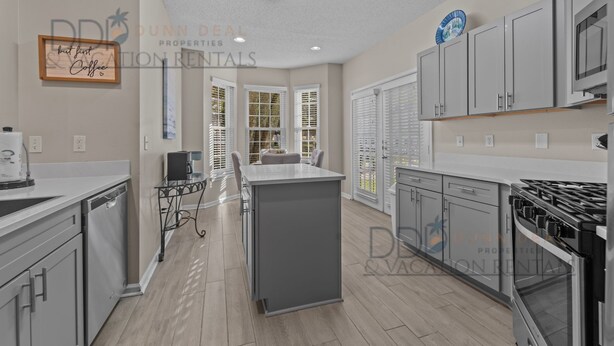 A modern kitchen with grey cabinets, a central island, and a built-in oven. - Legacy Villa 1701 | Just a Short Walk to the Beach! (Gulfport)