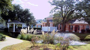 A residential area with a gazebo, a pond, and houses with arched windows and a pink facade. - Legacy Villa 1701 | Just a Short Walk to the Beach! (Gulfport)