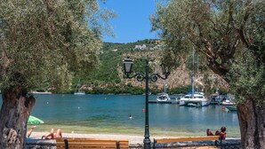 A lakeside park with benches, a lamp post, and boats on the water.