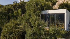 Um edifício moderno com grandes janelas de vidro, rodeado por vegetação densa.