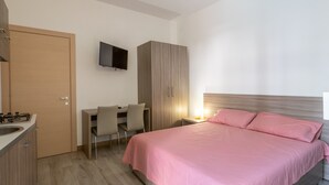Una camera da letto con un letto, una scrivania, una sedia, una TV e un armadio.