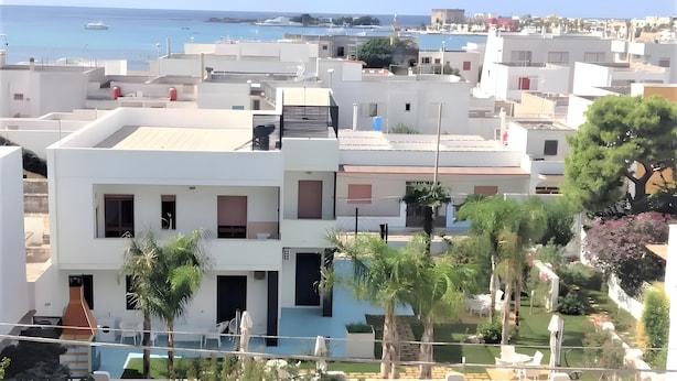Un quartiere residenziale con architettura moderna, una piscina e vista sul mare.