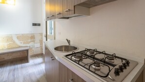 Una cucina moderna con piano cottura a gas, lavello in acciaio inox, mobili in legno e una panca.