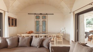 A cozy room with a large sofa, a dining table, and a view of the outdoors.