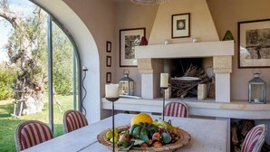 Ein Essbereich mit großem Tisch, Stühlen, einem Kamin und gerahmten Bildern an der Wand.