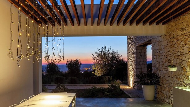 An outdoor patio with a table and chairs, a stone wall, and a view of the sunset. - Dietro al Muro - Four Bedroom Villa, Sleeps 10 (Avola)