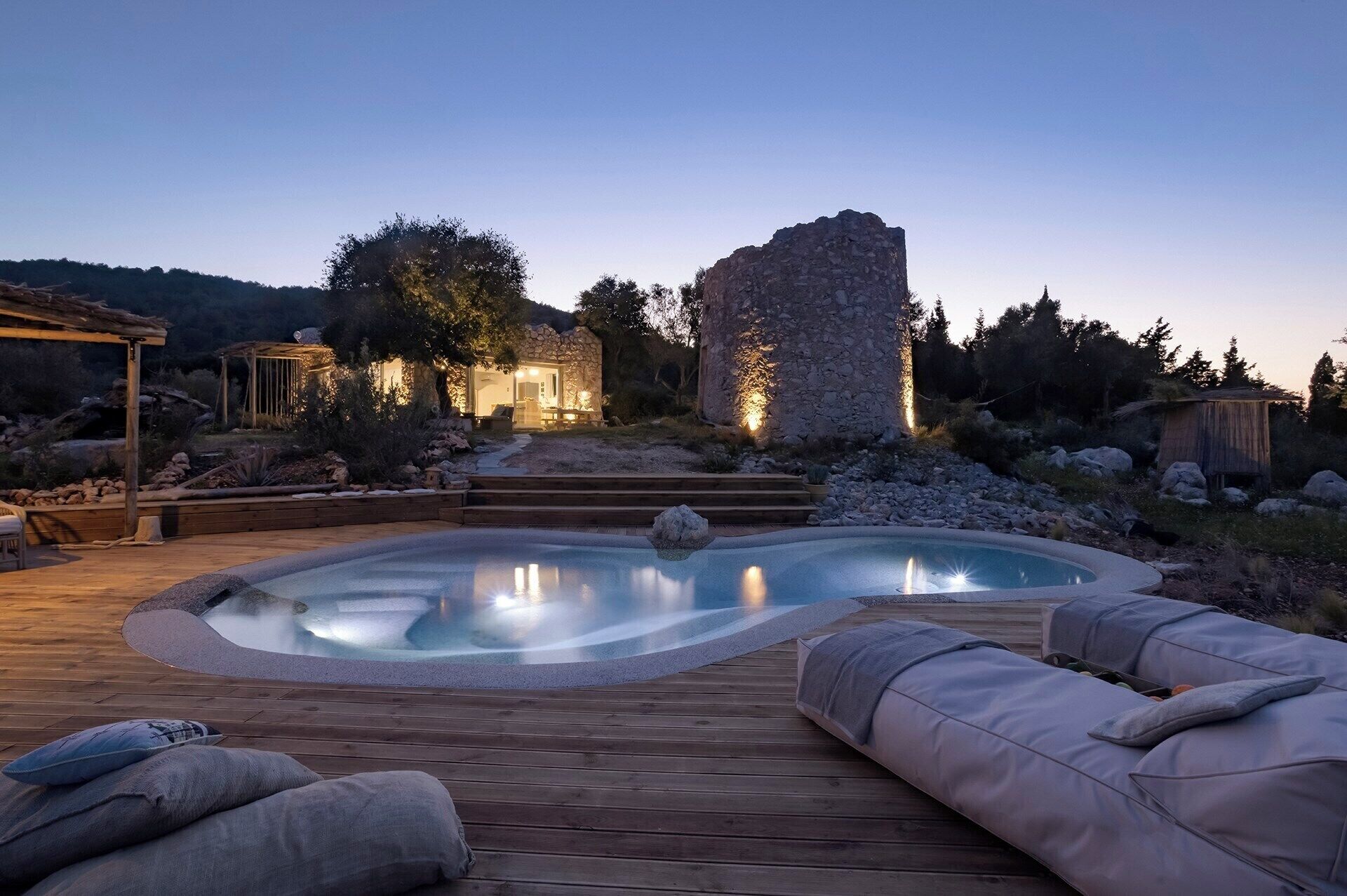 A pool area with a stone structure, wooden deck, and outdoor seating.