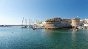A historic stone fort surrounded by calm waters with several boats docked nearby.