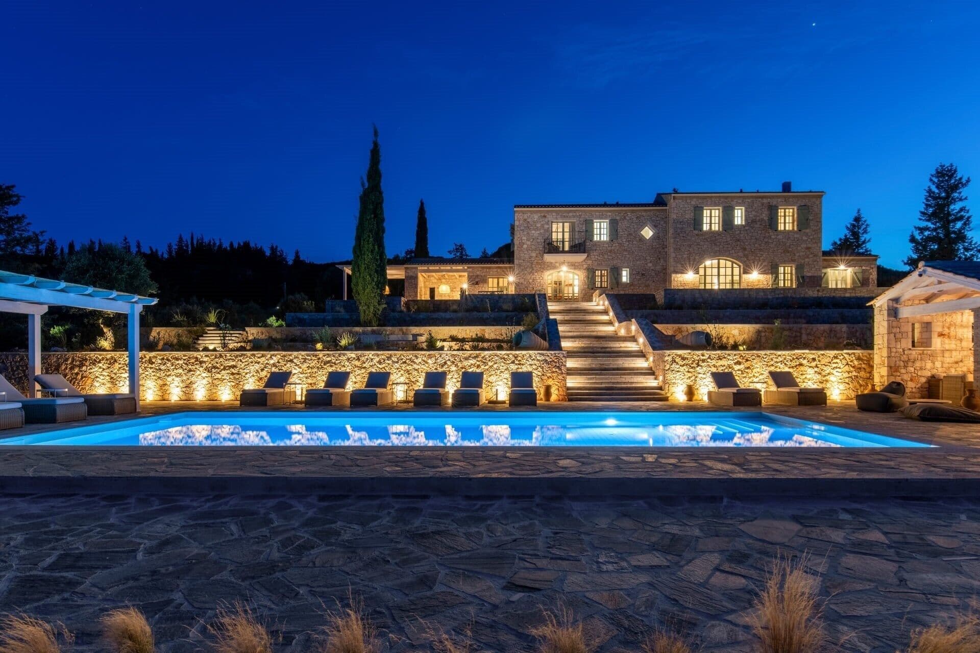 Un edificio de piedra con piscina, asientos exteriores y una escalera que conduce a la entrada.