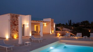 A modern poolside area with lounge chairs and a swimming pool, surrounded by stone walls and warm lighting. - Luna Rossa - Four Bedroom Villa, Sleeps 8 (Castrignano del capo)