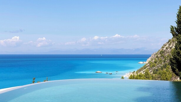A clear view of a coastal landscape with a large body of water, a sandy beach, and a rocky cliff with vegetation. - Madreterra - Six Bedroom Villa, Sleeps 12 (Lefkada)