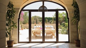 Un espace patio agrémenté d’une arche en pierre, d’un luminaire suspendu et de plantes en pot.