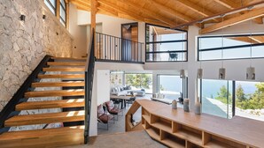 A spacious interior with a wooden staircase, a dining area, and large windows offering views of the outdoors. - Noiya - Eight Bedroom Villa, Sleeps 16 (Ponti Agiou Petrou)