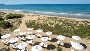 Een strand met witte parasols en ligbedden voor gasten.