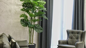 Una sala de estar moderna con una planta grande en maceta, un sofá gris y un sillón de cuero.