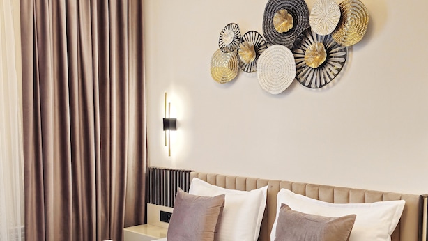 Una habitación de hotel con cama, almohadas, una lámpara de pared y un adorno mural.