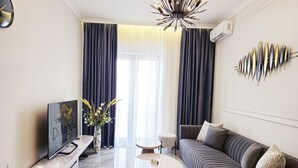 Una sala de estar moderna con sofá, mesa de centro, televisor y adornos.