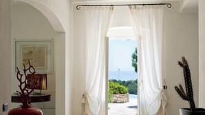 A doorway with white curtains, a red vase, and a cactus plant.