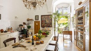 Una cocina amplia con una isla central, una araña y vistas a un jardín a través de un ventanal abierto.