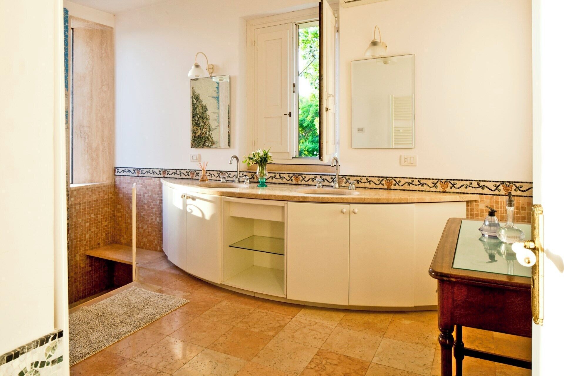 Une salle de bain moderne avec un meuble-lavabo aux lignes courbes, un grand miroir et une fenêtre laissant entrer la lumière naturelle.