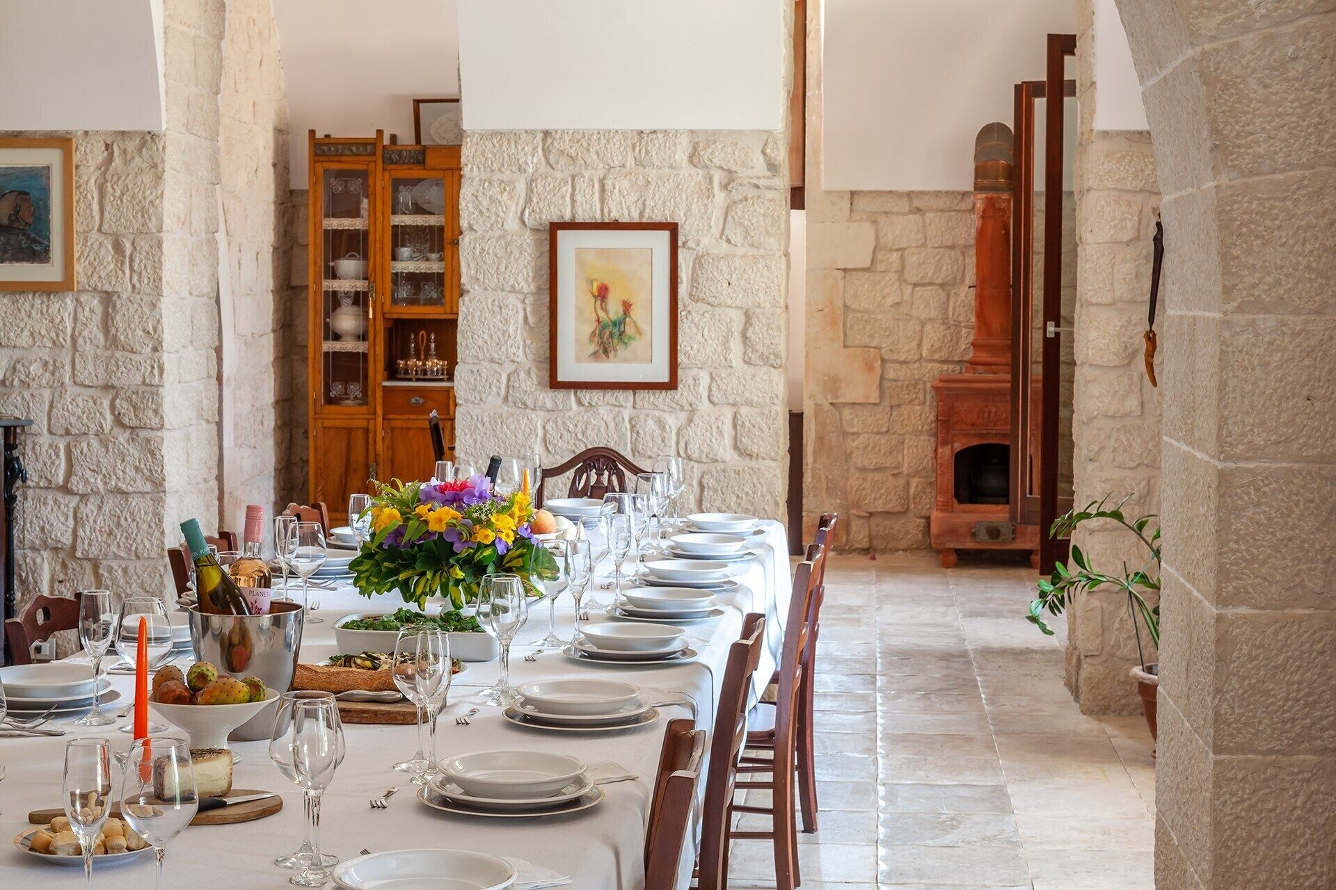 Un coin repas avec des murs en pierre, une cheminée et une table dressée pour le repas.