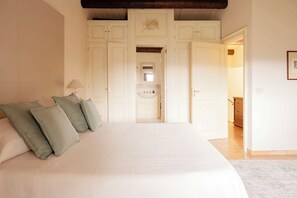 A bedroom with a large bed, a nightstand, a lamp, and a wardrobe with a mirror. - Villa San Tommaso - Four Bedroom Villa, Sleeps 8 (Syracuse)