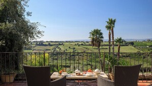 A terrace with wicker chairs and a table set for tea, overlooking a scenic landscape with hills and palm trees. - Villa San Tommaso - Four Bedroom Villa, Sleeps 8 (Syracuse)