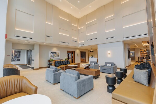 A spacious lobby with multiple seating areas, a reception desk, and a modern architectural design. - Highpoint Hotel (Sioux Falls)