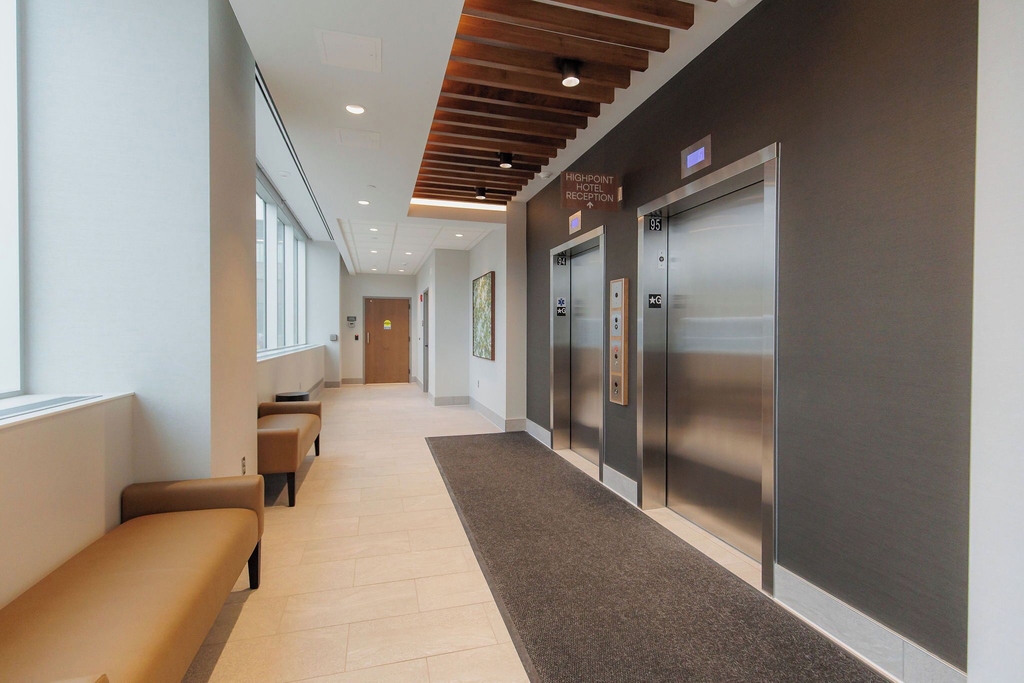 A hotel reception area with a long hallway, seating, and elevators.