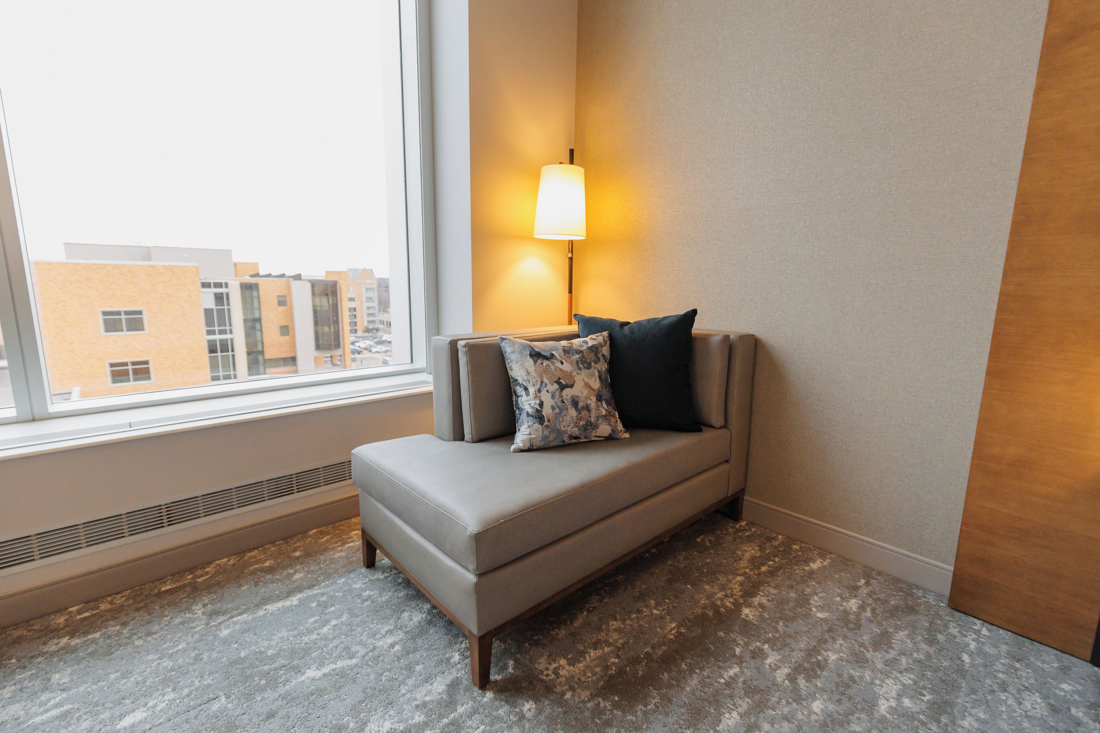 Habitación en esquina con sofá, lámpara, ventana y radiador.