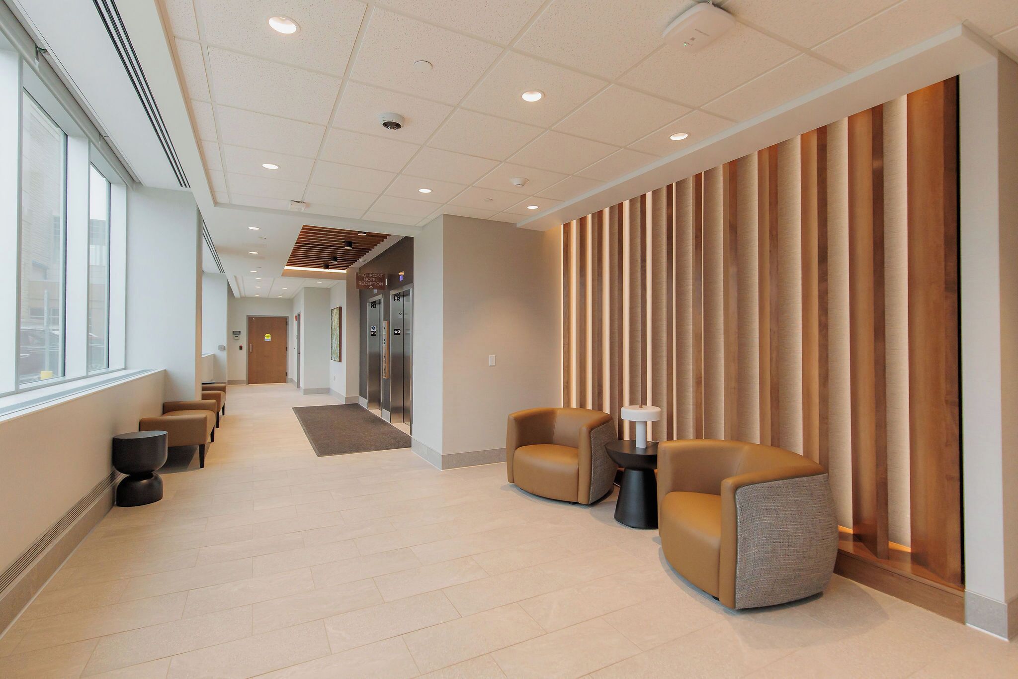 A modern lobby with a long corridor, seating area, and a reception desk.