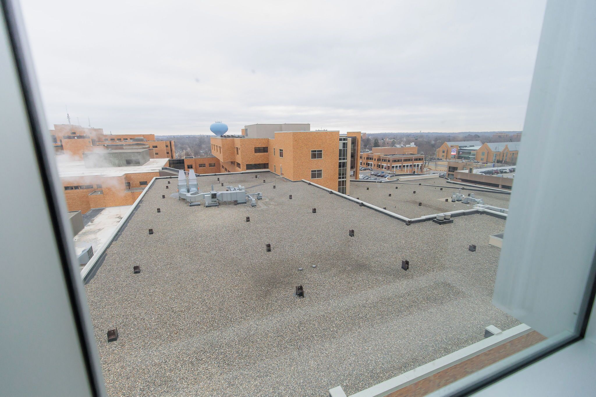 Terraço com vários edifícios, um reservatório de água e superfície de cascalho.