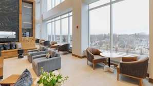 A spacious lobby with modern seating, large windows, and a city view. - Highpoint Hotel (Sioux Falls)