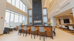 A modern bar area with a black marble column, bar stools, and a view of the city through large windows. - Highpoint Hotel (Sioux Falls)