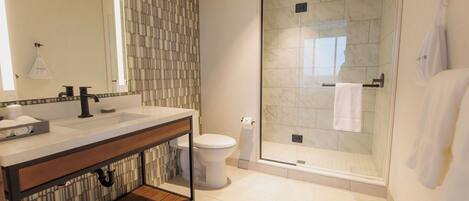 A modern bathroom with a glass-enclosed shower, a large mirror, and a wooden vanity.