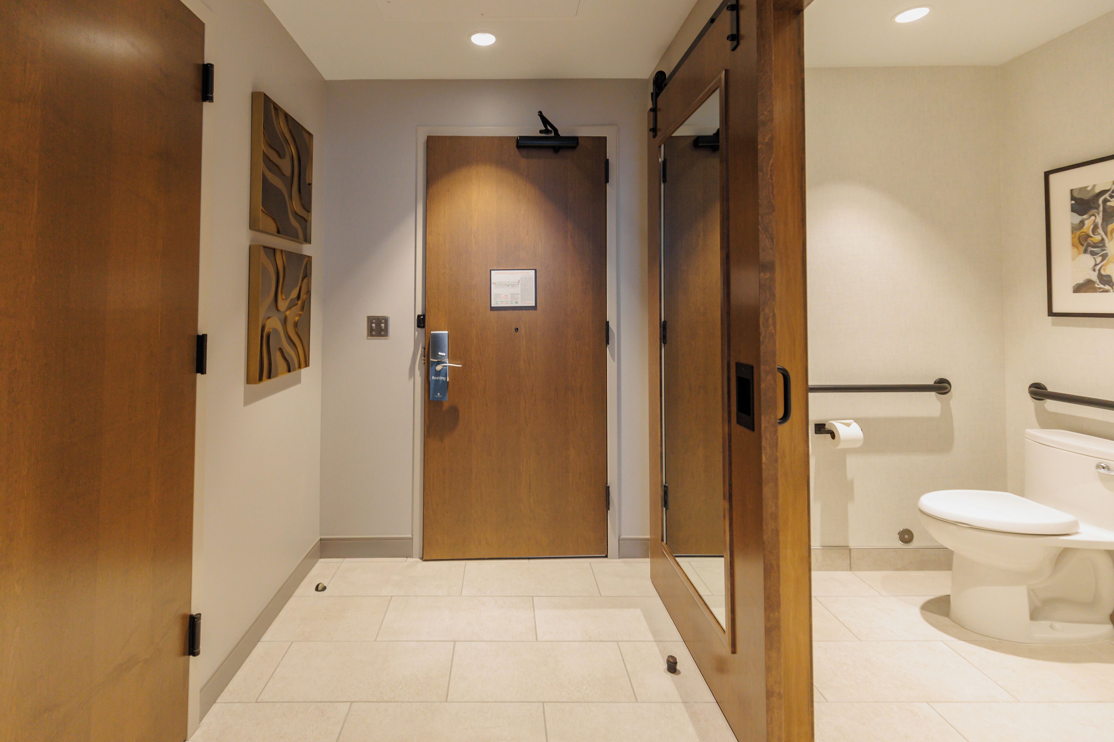 Une salle de bain moderne avec une porte en bois, des toilettes et un miroir.