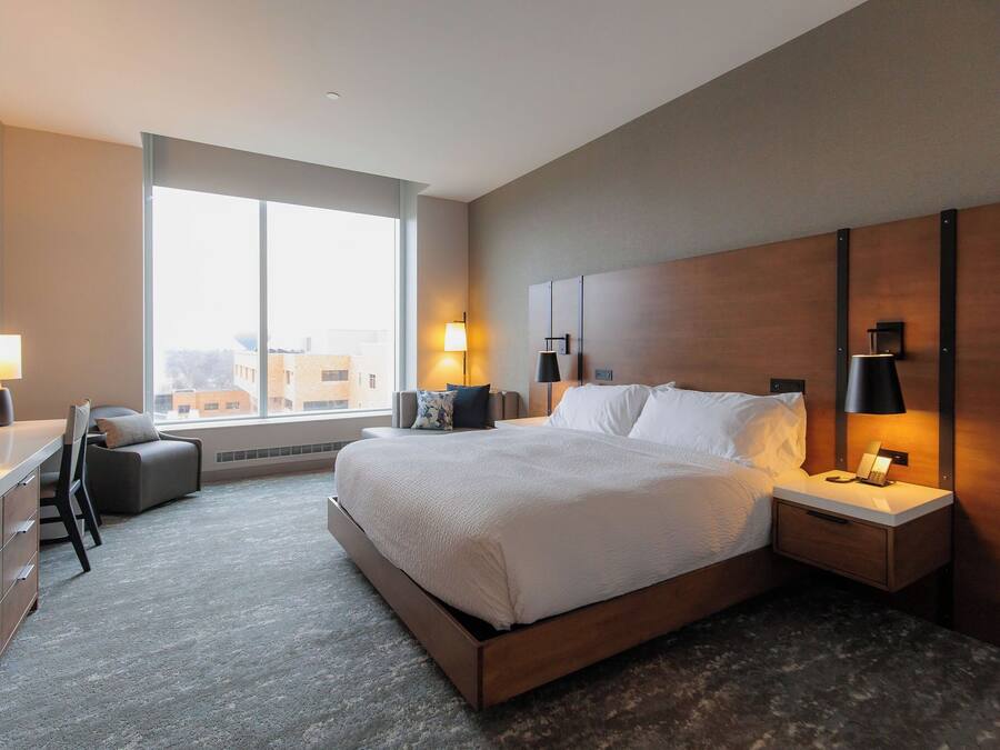 Una habitación de hotel moderna con una cama grande, mesitas de noche, un escritorio y una silla.