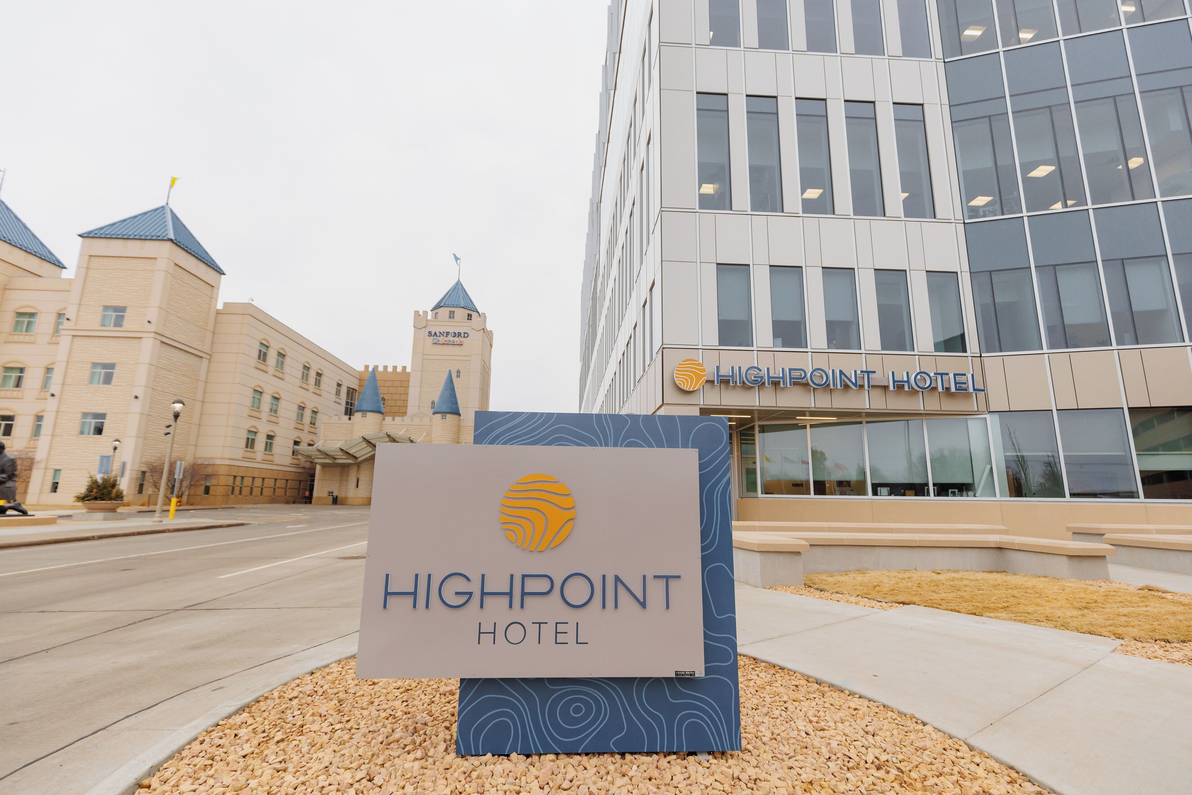 A hotel sign with a modern building in the background.