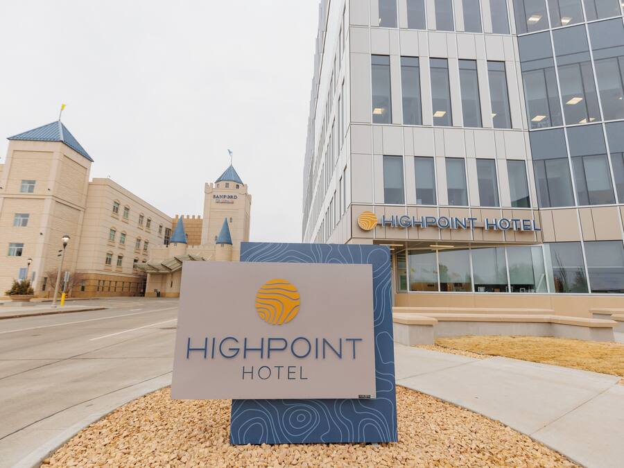 A hotel sign with a modern building in the background.